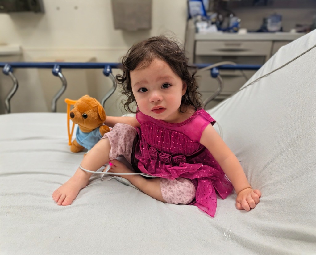 Jojo in a pink dress on a hospital bed